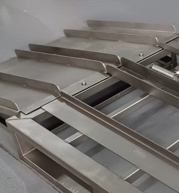 Close-up: Raised wheel guides on a stainless steel pallet ramp for tote bins